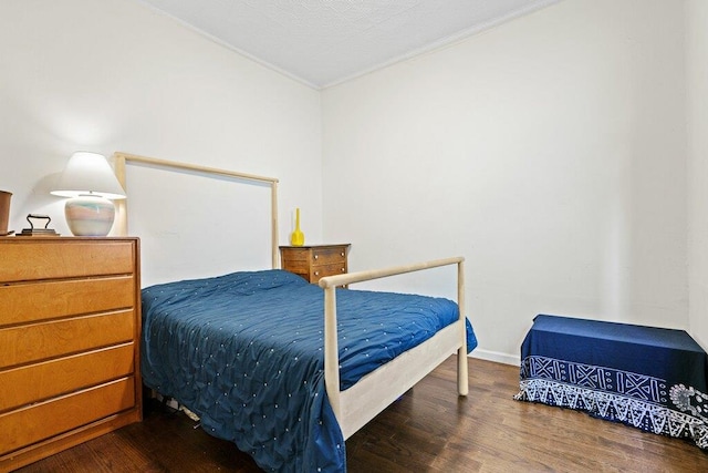 bedroom with crown molding, baseboards, and wood finished floors