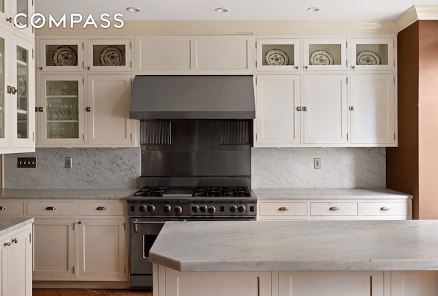 875 Park Ave Unit 9C, New York City, NY 10075 - kitchen with wall chimney range hood, stainless steel gas range oven, light stone counters, and tasteful backsplash