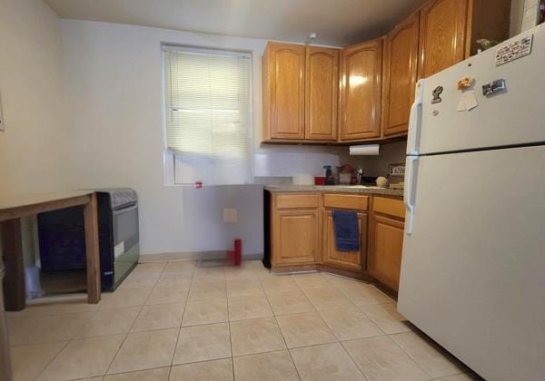 21-05 33rd St Unit 1-G, New York City, NY 11105 - kitchen featuring freestanding refrigerator, brown cabinetry, light tile patterned floors, and light countertops
