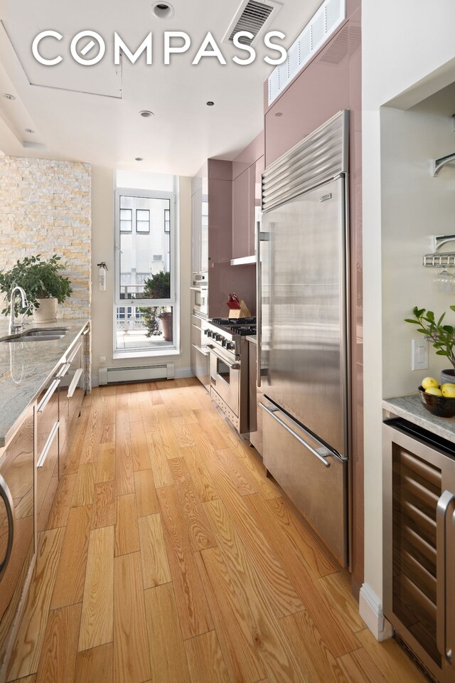 59 John St Unit Ph1, New York City, NY 10038 - kitchen with high quality appliances, a sink, wine cooler, a baseboard heating unit, and light wood-style floors