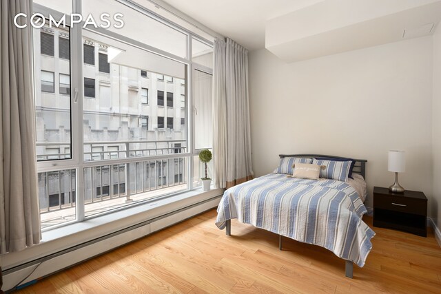 59 John St Unit Ph1, New York City, NY 10038 - bedroom featuring a baseboard heating unit and wood finished floors