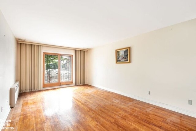 12 Girard St, New York City, NY 11235 - unfurnished room featuring radiator, light wood-style flooring, and baseboards