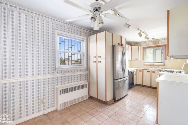 12 Girard St, New York City, NY 11235 - kitchen featuring radiator, appliances with stainless steel finishes, light countertops, light tile patterned floors, and wallpapered walls