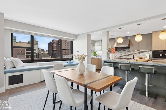 dining area featuring a view of city, a healthy amount of sunlight, and light wood finished floors