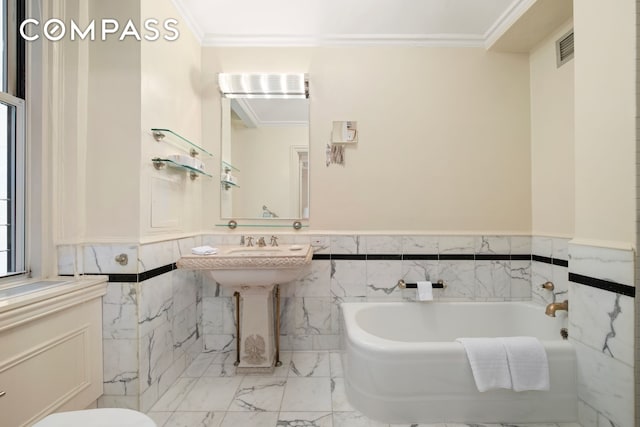 781 5th Ave Unit 514, New York City, NY 10022 - bathroom with ornamental molding, a garden tub, a wainscoted wall, tile walls, and marble finish floors