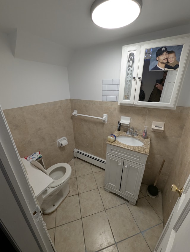 half bath featuring vanity, toilet, tile patterned floors, tile walls, and a baseboard heating unit