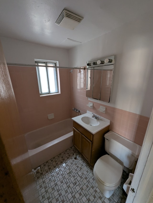 full bath with shower / bathtub combination, toilet, tile walls, and vanity