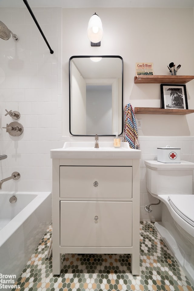 bathroom featuring toilet, tile patterned floors, washtub / shower combination, vanity, and tile walls