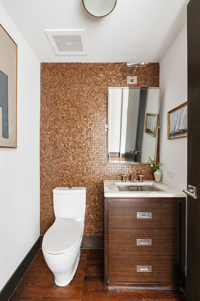 half bathroom featuring toilet, vanity, and baseboards