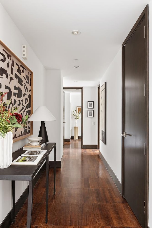 hallway featuring dark wood-style flooring, baseboards, and recessed lighting