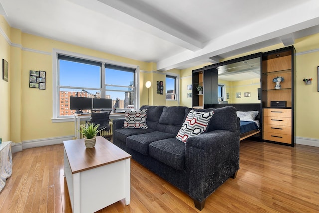 living room featuring baseboards, light wood-type flooring, and beamed ceiling