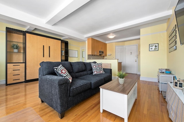 living room featuring light wood-style floors, beamed ceiling, and baseboards