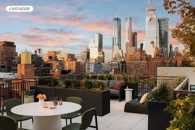 patio terrace at dusk featuring a skyline view, a balcony, and an outdoor hangout area