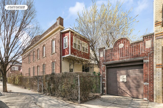 view of property featuring a garage, driveway, and fence
