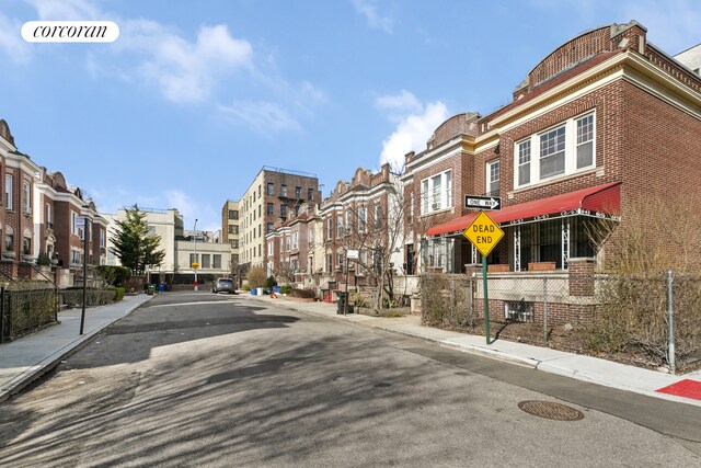 view of road featuring traffic signs, a residential view, curbs, and sidewalks