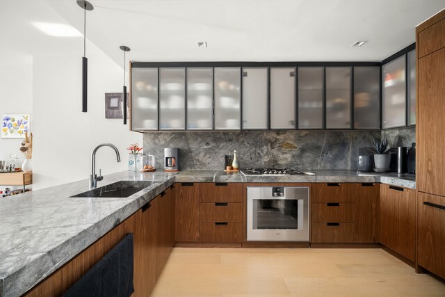 269 4th Ave Unit 403, New York City, NY 11215 - kitchen with appliances with stainless steel finishes, a sink, glass insert cabinets, backsplash, and brown cabinets