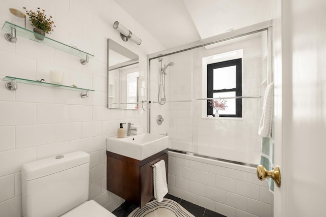 full bath with tiled shower / bath combo, toilet, tile walls, and vanity
