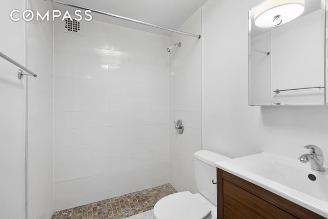 full bath featuring a tile shower, vanity, and toilet