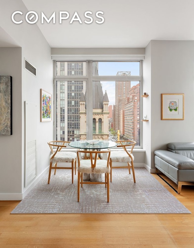 dining room with baseboards, wood finished floors, and a view of city