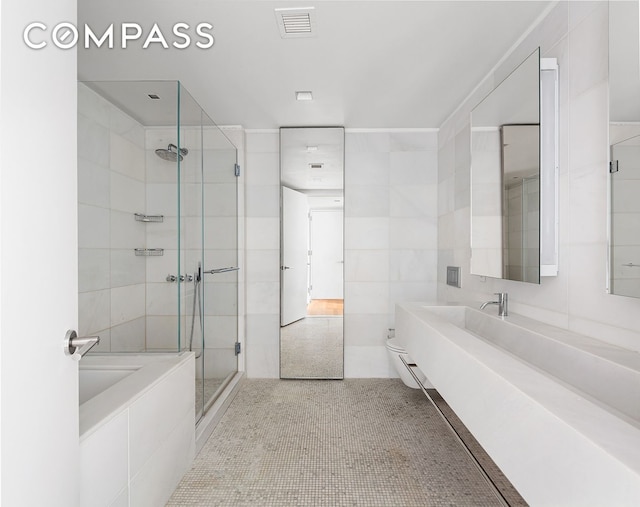 bathroom with a shower stall, tile walls, a tub to relax in, and vanity