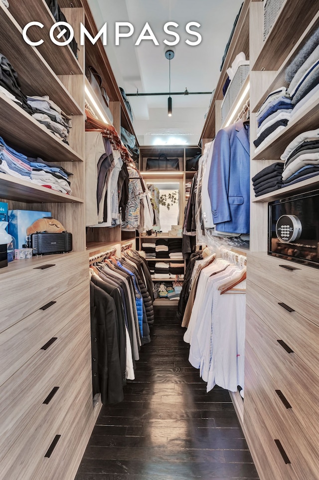 walk in closet with dark wood-style flooring