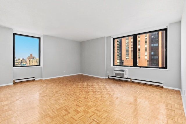 empty room featuring a baseboard heating unit, plenty of natural light, and baseboards