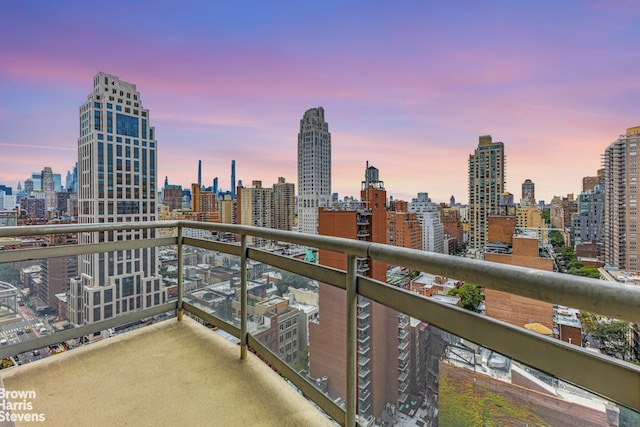 balcony at dusk featuring a skyline view