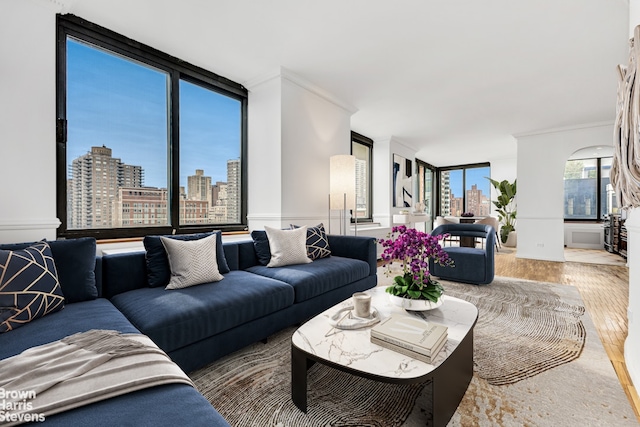 living area with wood finished floors, crown molding, a view of skyline, and a wall of windows