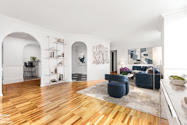 living room featuring arched walkways and ornamental molding