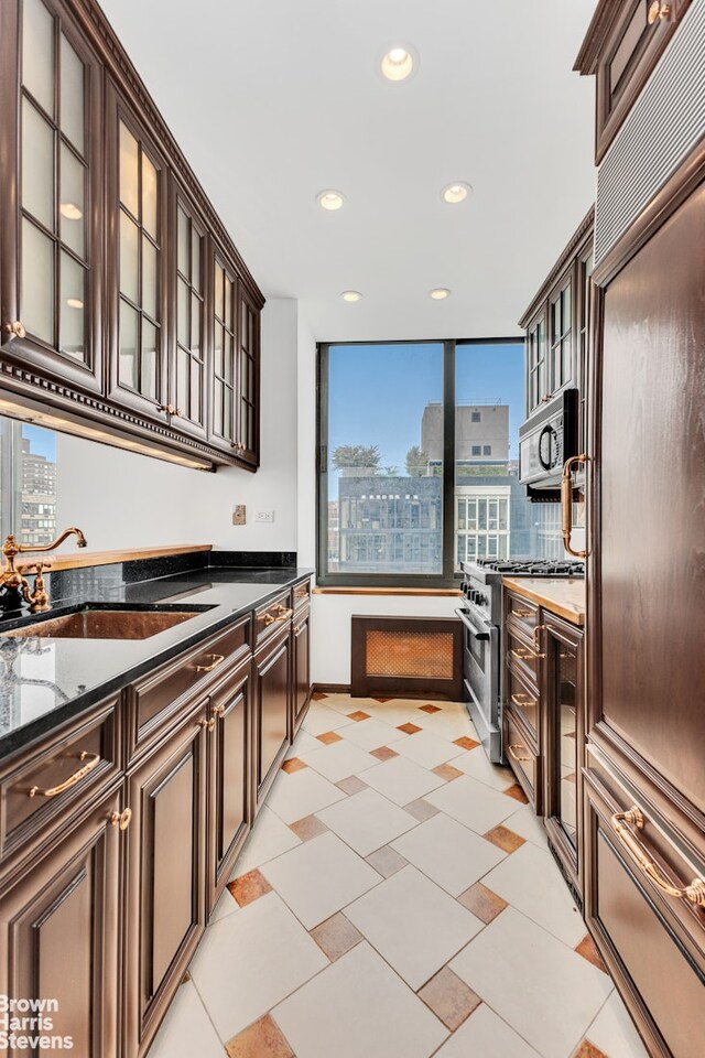 kitchen featuring high quality appliances, dark brown cabinetry, a sink, recessed lighting, and wine cooler