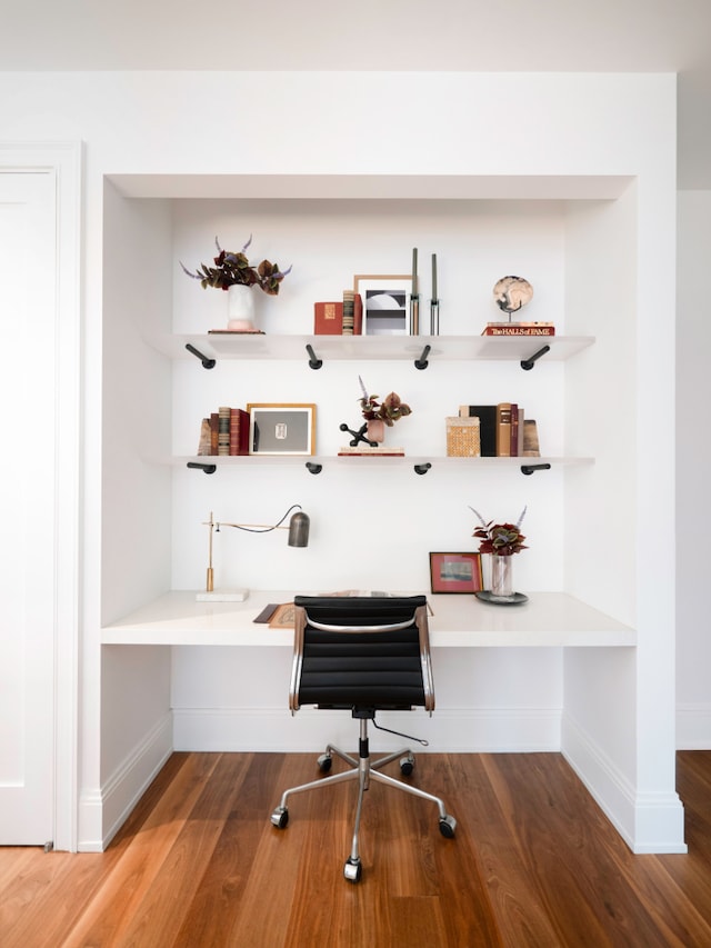 home office with built in study area, baseboards, and wood finished floors