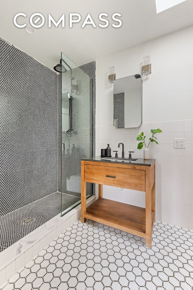full bath with tile walls, wainscoting, tiled shower, and vanity