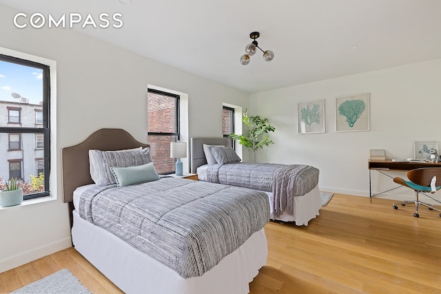 bedroom featuring baseboards, multiple windows, and light wood finished floors