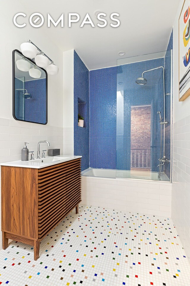 bathroom with vanity, tile patterned floors, a tub, tile walls, and tiled shower