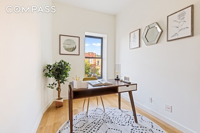 office space with baseboards and light wood finished floors