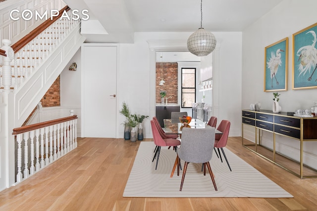 dining space with stairway, wainscoting, and wood finished floors