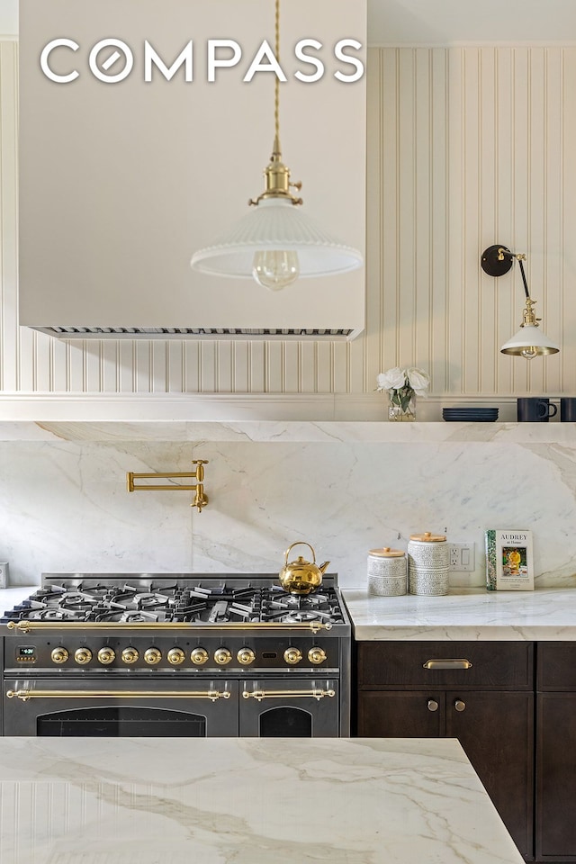 kitchen featuring light stone counters, exhaust hood, double oven range, and dark brown cabinets