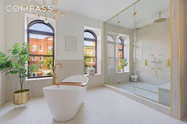 bathroom featuring wainscoting, a freestanding bath, a chandelier, and a shower stall