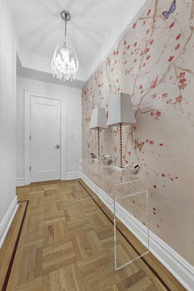 corridor with baseboards and a chandelier