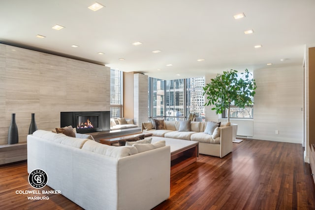living area featuring recessed lighting, baseboards, dark wood finished floors, and a high end fireplace