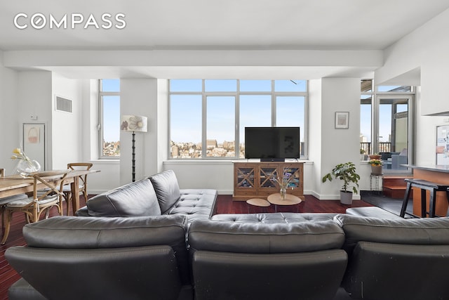living area featuring dark wood-type flooring, plenty of natural light, and baseboards