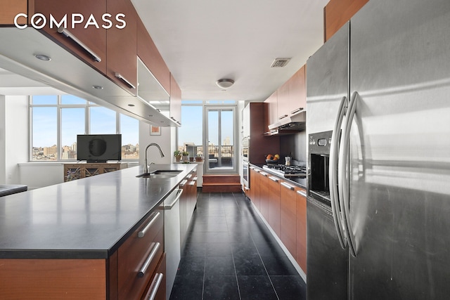 kitchen featuring appliances with stainless steel finishes, a sink, plenty of natural light, and dark countertops