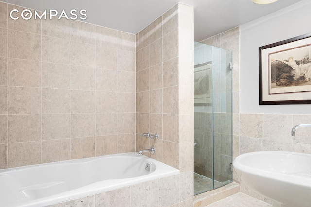 bathroom featuring tile walls, a stall shower, and a relaxing tiled tub