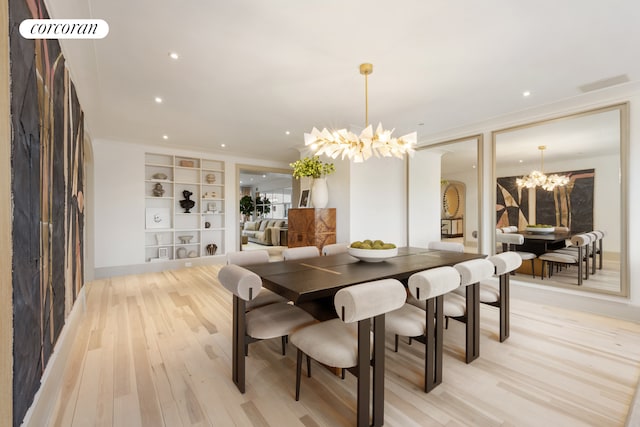 dining space featuring a chandelier, light wood-type flooring, built in shelves, crown molding, and recessed lighting