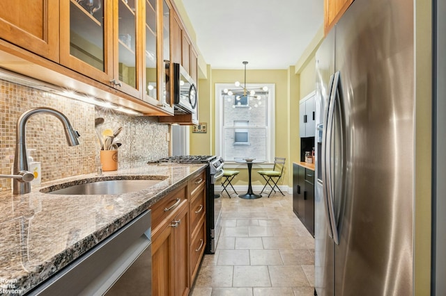 kitchen with stainless steel appliances, a sink, brown cabinets, and backsplash