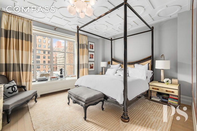 135 E 79th St Unit 8E, New York City, NY 10075 - bedroom featuring wood finished floors and a chandelier