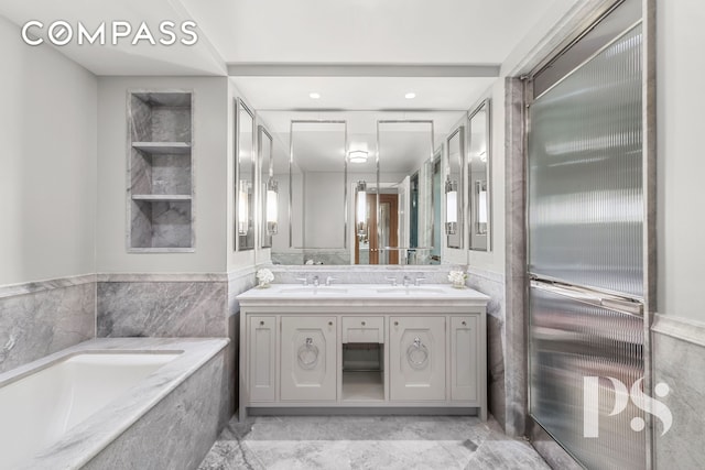 135 E 79th St Unit 8E, New York City, NY 10075 - bathroom with double vanity, a garden tub, tile walls, marble finish floors, and a wainscoted wall