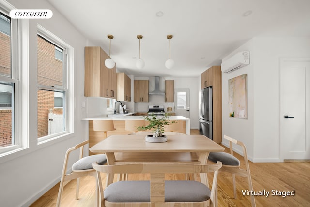 dining area featuring baseboards, a wall mounted AC, and light wood-style flooring