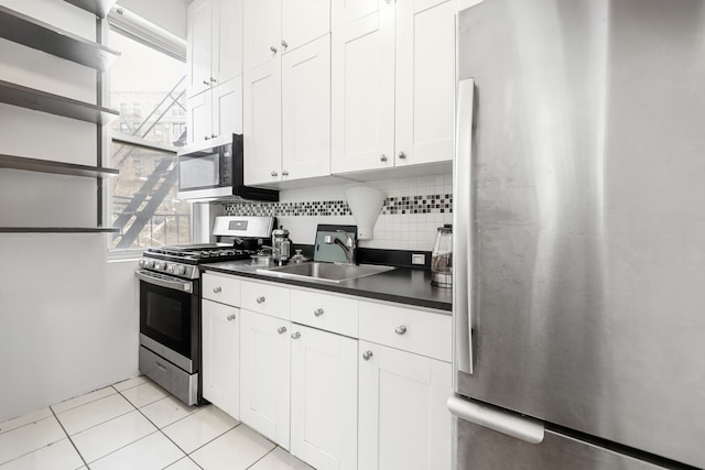 867 Riverside Dr, New York City, NY 10032 - kitchen featuring appliances with stainless steel finishes, a sink, dark countertops, white cabinets, and decorative backsplash