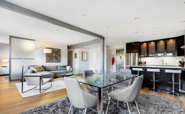dining room with light wood-style flooring, wet bar, and recessed lighting